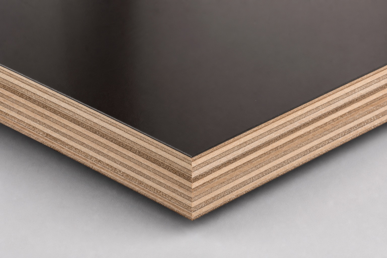 Corner of thin film-faced plywood with smooth glossy phenolic face and cross-laminated wood-edge core